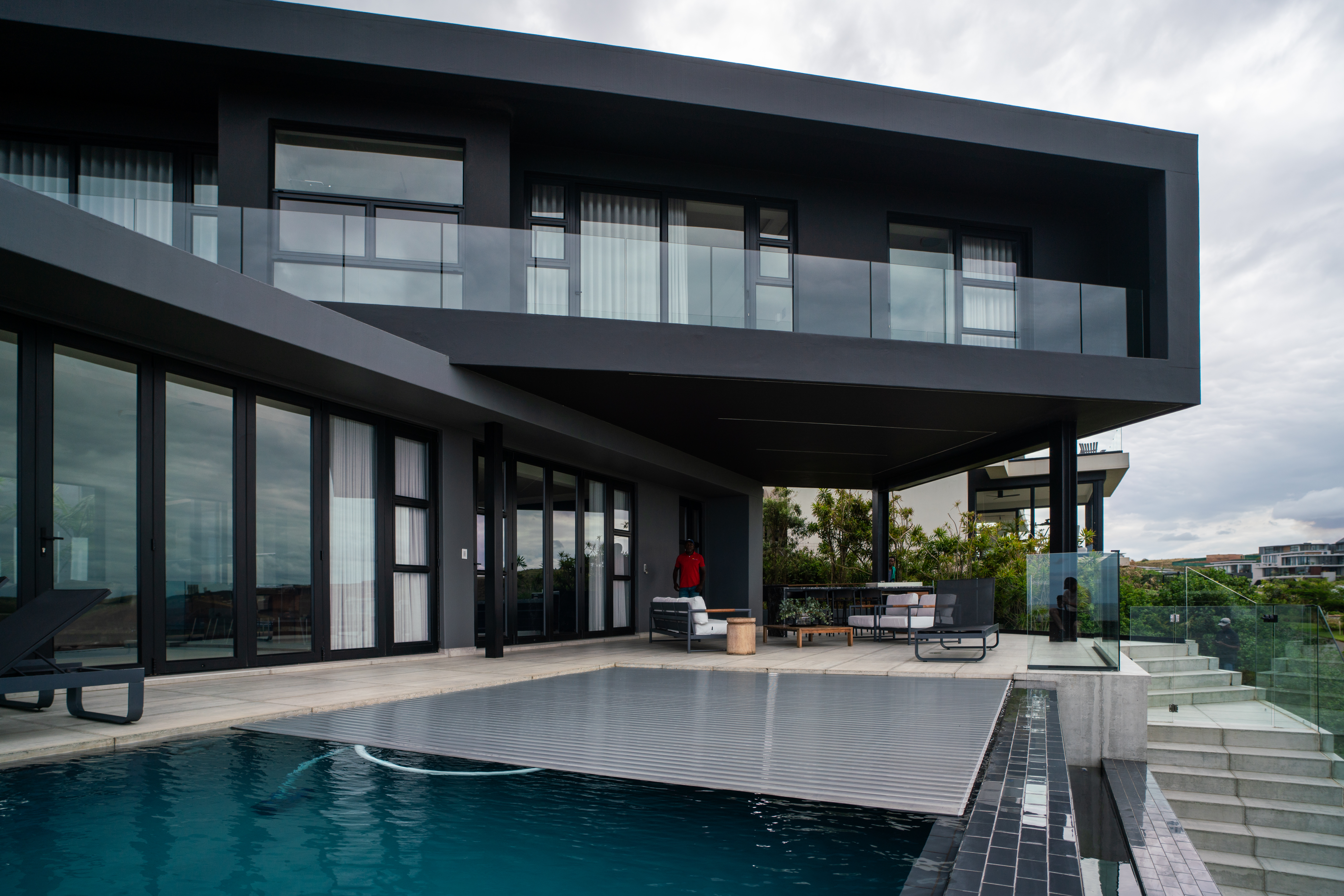 Modern luxury pool with PoolDeck slatted automatic cover - showing elegant black architecture and walkable cover surface