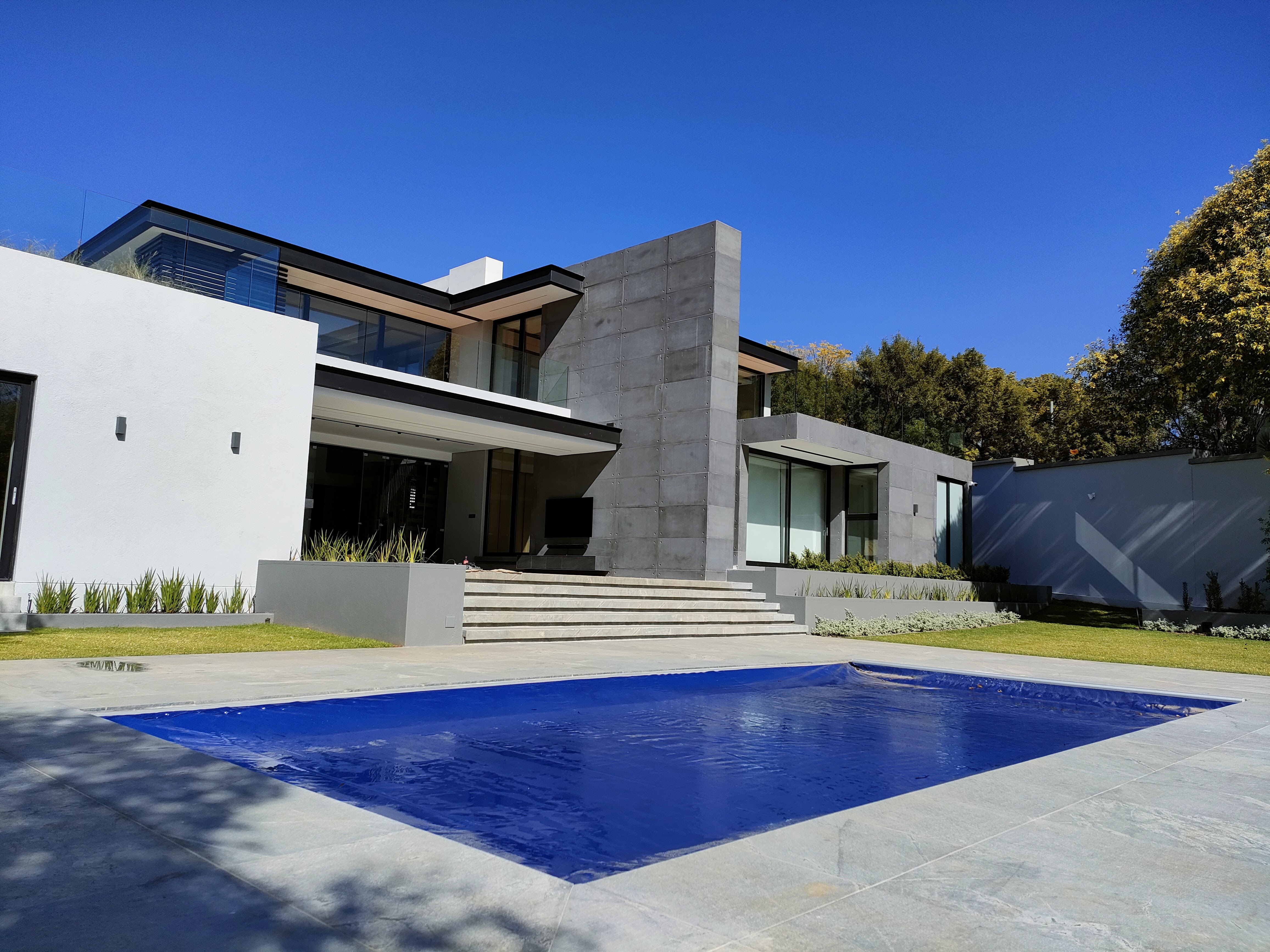 Modern family pool with automated pool cover partially open showing crystal clear water